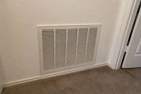 Single large return-air grille set into a hallway wall, painted the same color as the wall