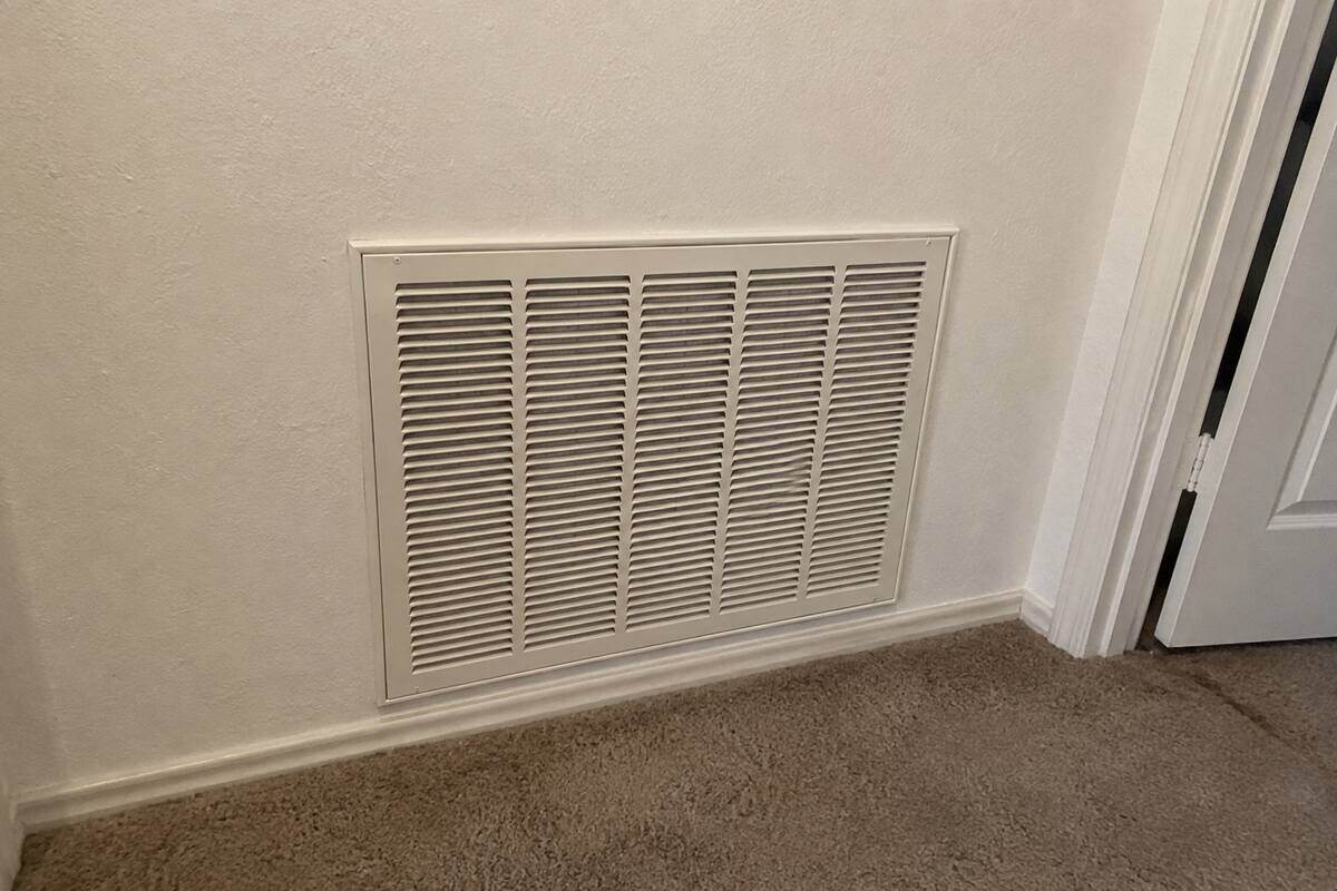 Single large return-air grille set into a hallway wall, painted the same color as the wall