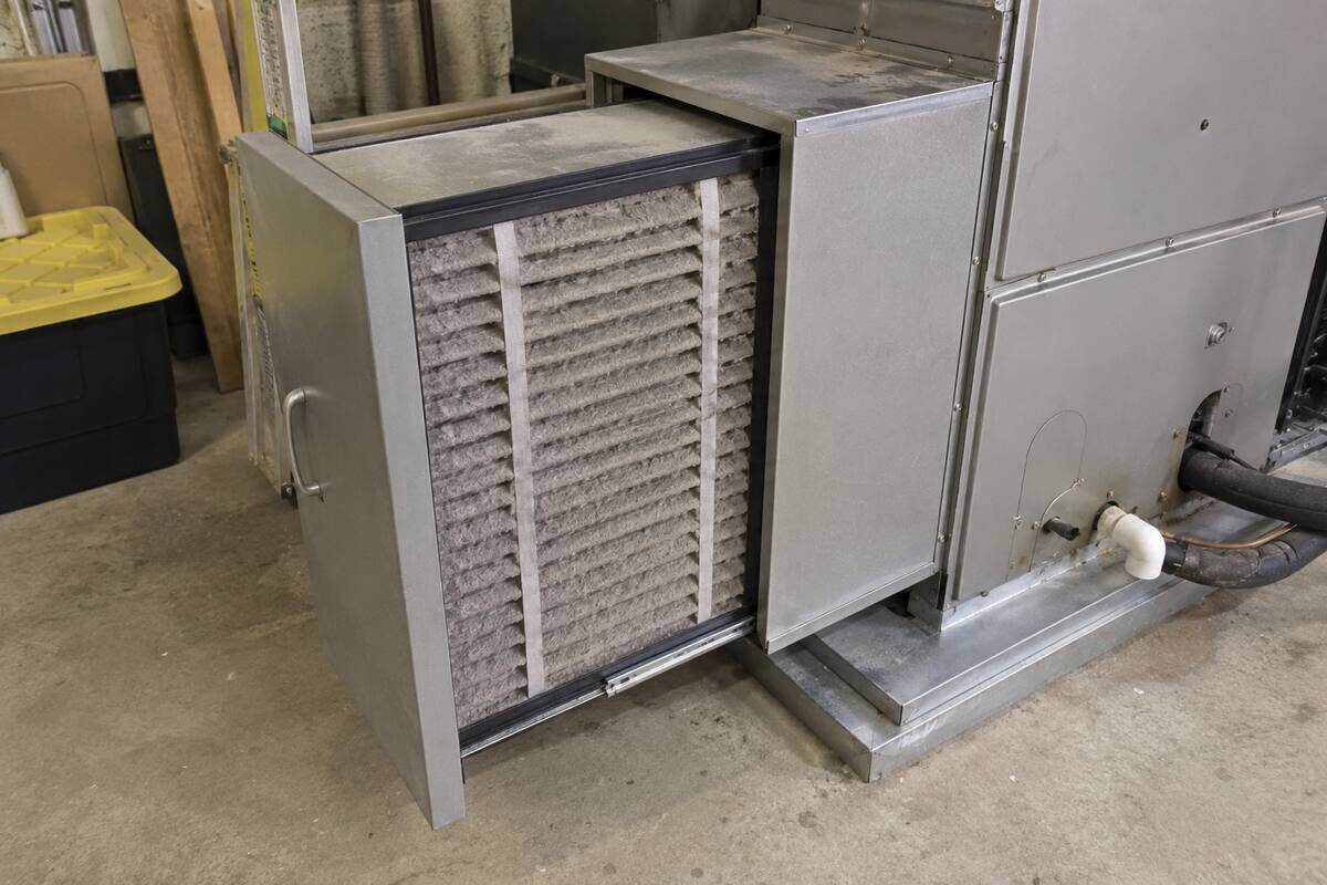 Deep media filter cabinet beside an air handler with the pleated cartridge pulled half way out